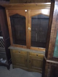 A late 19thC Continental pine cabinet, the top with a moulded cornice above two arched glazed doors enclosing adjustable shelves, the base with two frieze drawers and two panelled doors, on bracket feet, 202cm high, 122cm wide, 46cm deep.