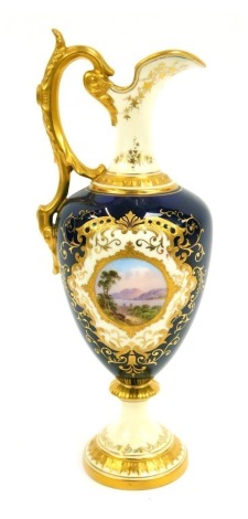 A late 19thC Coalport porcelain jug, of baluster form, with a foliate scroll handle, decorated with a central reserve painted with a lakeland landscape, against a cobalt blue ground, gilt heightened, printed and painted marks, 26cm high.