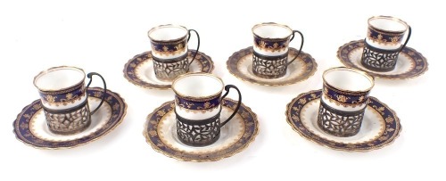 A set of Aynsley demitasse porcelain coffee cans and saucers, with gilt foliate decoration against a cobalt blue ground, the cups with silver pierced foliate cup holders, Birmingham 1925.