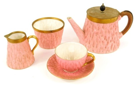 A Coalport porcelain solitaire set, with brass mounts, of pink moulded tree form, printed marks, comprising teapot, cream jug, sugar bowl, cup and saucer.