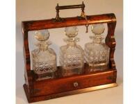 A late 19thC oak Tantalus with three cut glass decanters