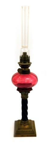 A Victorian miniature oil lamp, with a brass Corinthian column and stem, cranberry glass reservoir with chimney, 46cm high.