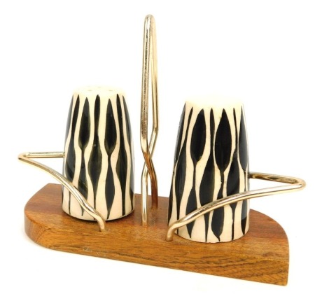 A pair of mid century salt and pepper shakers, white ceramic ground with black patterned detail, on a teak shaped base, 12cm high, 11cm wide.