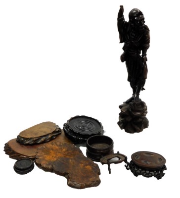 A Chinese wooden carving of an Immortal, modelled standing, his left foot upon a wild beast, on a rocky base, 46cm high (AF), together with hardwood wooden stands. (a quantity) - 5