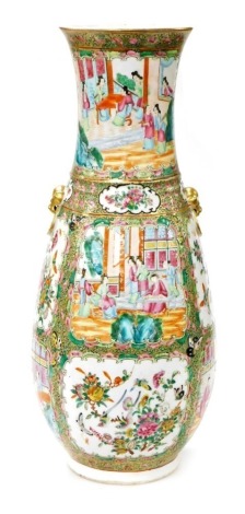 A late 19thC Qing Dynasty Cantonese famille rose porcelain vase, of baluster form, with twin lion's head and ring handles, decorated with reserves of figures in interiors, birds, butterflies, and flowers, within a floral and gilt ground, 60.5cm high.