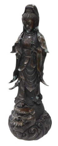 A Qing Dynasty bronze figure of Guan Yin, modelled standing, on a dragon fish, above a scrolling wave base, 101cm high.