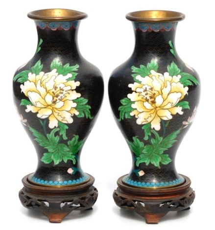 A pair of Chinese cloisonne baluster vases, on a black ground with blue borders and cream and pink flowers with butterflies on pierced bases, 17cm high. (2)