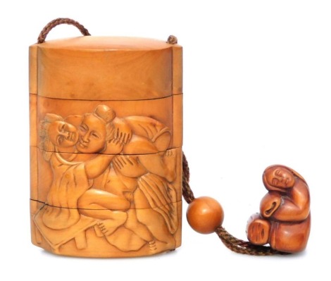 A Japanese carved wood three case inro, carved with male and female figures in erotic positions (shunga), with carved wood netsuke of a woman, 9cm high.