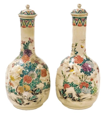 A pair of Meiji period Japanese Satsuma bottle vases and covers, of lobed form, enamel decorated with birds and flowers, 24cm high.