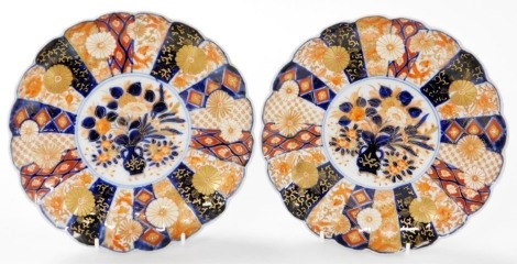 A pair of Meiji period Japanese porcelain Imari dishes, of fluted form, decorated centrally with a vase of flowers, within a border of panels of birds and chrysanthemums, 22cm wide.