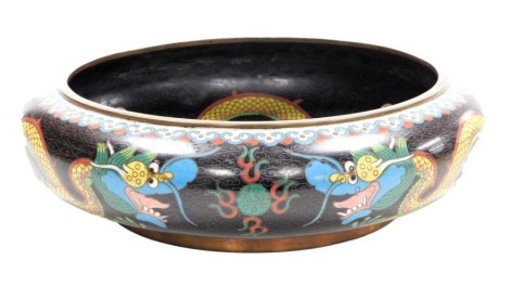 A Chinese cloisonne bowl, the interior decorated with a figure of a four clawed dragon, the outer border decorated with dragons on a black ground, four character "Ming" mark to underside, 29cm diameter.