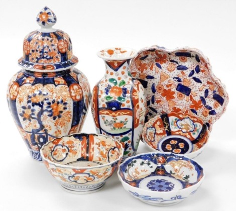 A group of Japanese Imari wares, comprising vase and cover, 32cm high, a vase of cylindrical tapering form with flared neck, three bowls and a dish with a petal shaped rim, 23cm diameter.