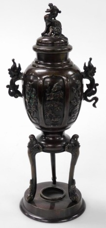 A 19thC Chinese bronze koro and cover, the cover with dragon finial, the body with twin dragon handles, decorated in bas relief with panels of birds and blossom, raised on an integral table base and circular foot, 34cm high. (AF)