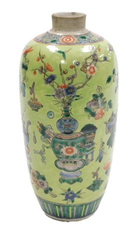 A late 19thC Qing Dynasty porcelain vase, of ovoid form, decorated with Buddhist emblems, vases of flowers, fruit, etc., on a lime green ground, 24cm high.