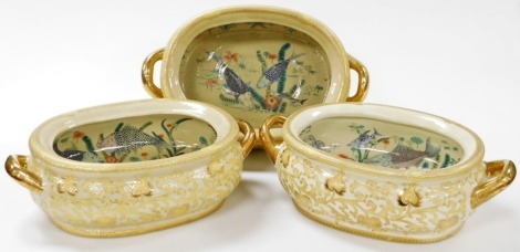 Three Chinese twin handled porcelain goldfish bowls, of oval form, decorated internally with fish, crabs, and pond fauna, the exterior with flowers and scrolling leaves on a cream ground, 48cm wide.