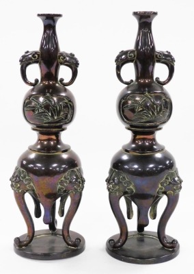 A pair of Japanese bronze vases, of twin handled baluster form, decorated in bas relief with panels of birds and dragonflies, raised on three lion's head capped cabriole legs, 21cm high. - 2