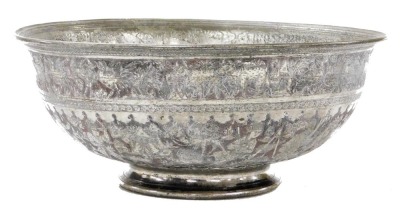 A late 19thC Indo Persian white metal bowl, embossed with figures, tents and animals, beneath a border of exotic birds, 32.5cm wide.