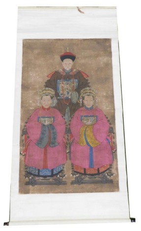 A Chinese ceremonial ancestor portrait scroll, depicting a high ranking court official with two of his wives dressed in pink, watercolour on silk, 210cm x 103cm.