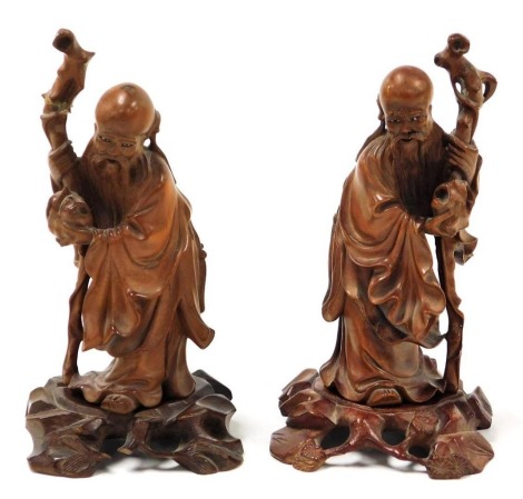 Two 19thC Chinese carved hardwood figures of sages, each holding a gnarled staff, 15cm high.