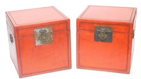 A pair of Chinese red lacquer chests, of square section, with twin carrying handles, each 40cm high, 40cm wide, 40cm deep.