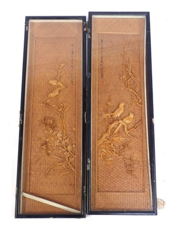 A pair of 20thC Japanese bird panels, each with a cane background, raised relief decoration of birds perched on branches with blossom, calligraphy to upper left and right sides respectively, 87cm x 26cm, framed and glazed.