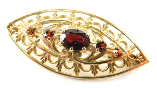 A 9ct gold garnet set pierced elliptical brooch, 3.9g all in.