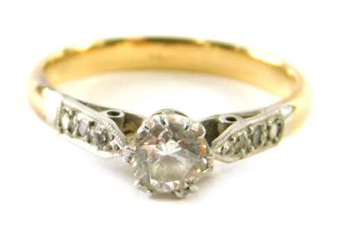 A solitaire diamond ring, 0.20ct approx diamond with tiny stone set shoulders on yellow metal shank, size I, 2g all in.