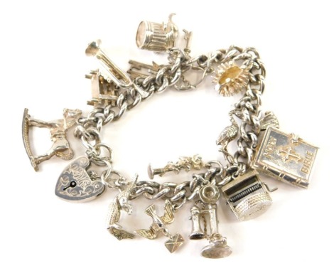 A curb link charm bracelet with padlock clasp and thirteen attached charms, white metal.