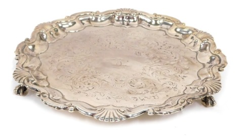 An Edward VII silver pie crust salver, etched with scrolls with central crest, on triple claw and ball feet, Reid and Sons Newcastle Upon Tyne retailers mark, London 1909, 22cm wide, 11oz.