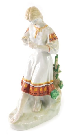 A Ukrainian Polonoye figure of a girl counting daisies, marked beneath, 37cm high.