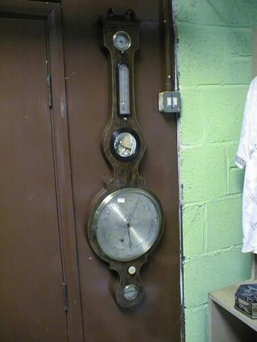 An early 19thC flamed mahogany wheel barometer with swan neck pediment