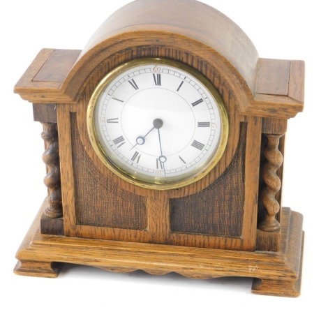 A mid 20thC oak cased mantel clock, the 8cm diameter Roman numeric dial flanked by turned columns.