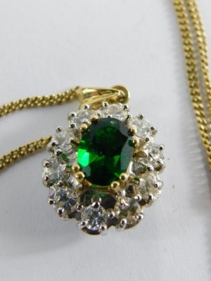 An emerald and CZ pendant, the pendant set with central oval heat treated emerald, 8mm x 5.8mm x 3.8mm, surrounded by eight round brilliant cut cz stones in claw platinum setting, unmarked on a gold fine link neck chain, the pendant 2.5cm high, the chain - 2