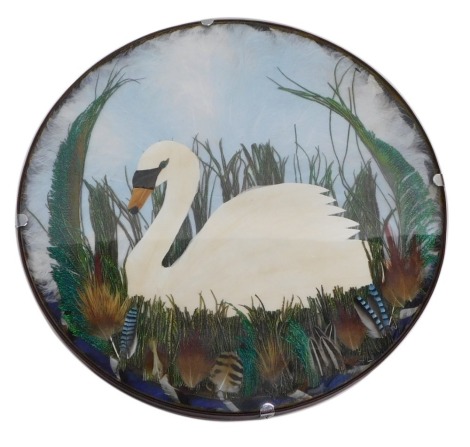 A 20thC feather collage swan in reeds, using various birds feathers, peacock feathers, etc. unsigned, 31cm diameter.