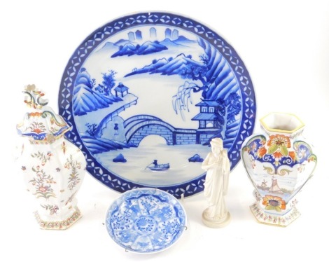 A Japanese porcelain blue and white plate, decorated with bridge before hills, 31cm diameter, a Chinese porcelain saucer with double circle mark, Parian figure of Cyprus and two tin glazed earthenware lidded vases decorated with flowers. (a quantity, AF)