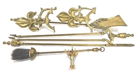 A Regency style brass fireside companion set, with two fleur de lys andirons, 24cm high, shovel, brush, coal nips, etc. (a quantity)