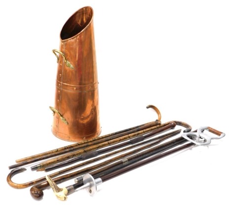 Various walking sticks, shooting stick, silver tipped and other examples, horn handled walking stick, etc., contained in a copper and brass coal bucket, 54cm high.