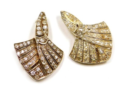 A pair of Art Deco diamond brooches, of scrolling, fan shaped form, set with rose and old cut diamonds in white and yellow metal mounts, each brooch having sixty one diamonds, one diamond lacking, 10.4g.