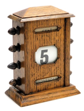 An early 20thC oak cased perpetual desk calendar, 15cm high.