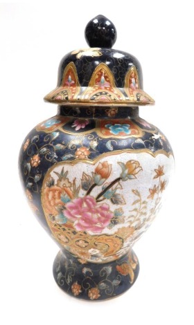 A 20thC Chinese famille noire jar and cover, decorated with reserves of flowering branches, against a dark blue ground with further flowers, six character seal mark to underside, 37cm high.