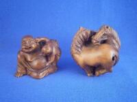 A carved wooden netsuke in the form of Pudai and another of two