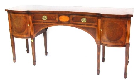 A Titchmarsh and Goodwin Sheraton Revival mahogany and inlaid serpentine fronted sideboard, the shaped top above a frieze drawer, flanked by two doors, on tapering spade legs, bears label, 94cm high, 197cm wide, 60cm deep.