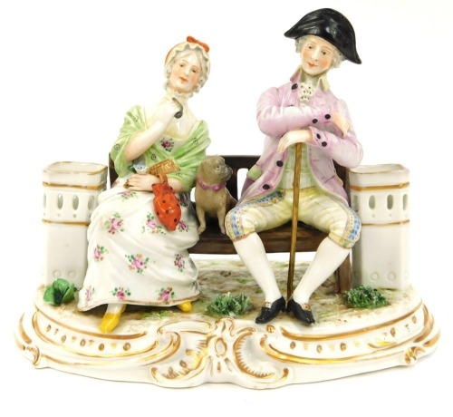 A Continental porcelain figure group, of two figures seated on a bench, depicting male and female with pug, 15cm high, 17cm wide.