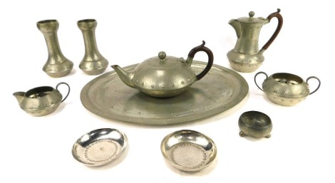 An Arts and Crafts pewter tea set, stamped Homeland, by W and Co, comprising teapot, coffee pot, milk jug, sugar bowl, two hammered candlesticks and two Keswick Firth pewter pin dishes.