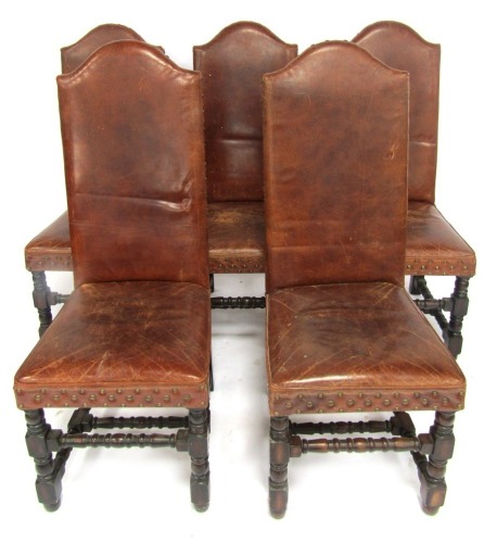 A set of five Artsome for Coach House Collection brown leather high back chairs, each with a shaped back with stud work, raised on oak turned legs, with turned stretchers, each 114cm high.