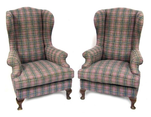 A pair of 20thC wingback armchairs, upholstered in purple tartan fabric, raised on mahogany hoof feet, 120cm high, 88cm wide.