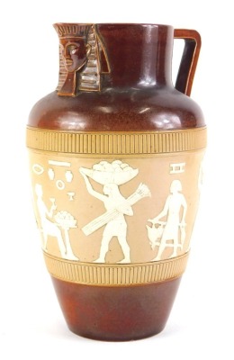 A Doulton Lambeth stoneware jug, decorated with a band of Egyptian figures, with angular handle and sphinx mask to spout, indistinct impressed mark to underside, 25cm high.