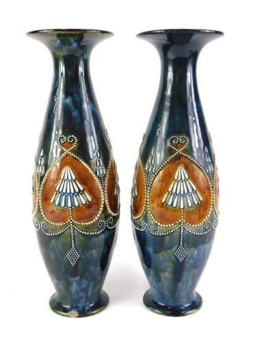 A near pair of Royal Doulton stoneware vases, each with a flared rim, the body with raised bead work decoration in stylised hearts, on a domed foot, impressed marks to underside and decorators initials limited edition PB and MH, possibly Marion Holbrook,