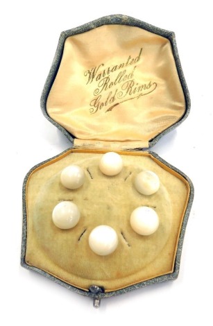 A cased set of six mother of pearl collar studs, with rolled gold rims, boxed.