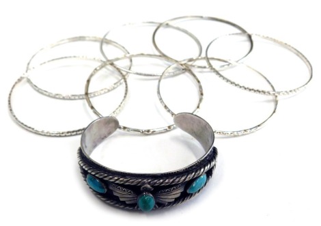 A group of bangles and bracelets, to include an eagle bangle, set with three turquoise stones, white metal, unmarked, and seven various silver coloured bangles.